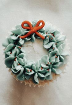 a cupcake decorated with blue frosting and an orange bow