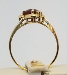 "We do not check prongs for wear or stones for looseness. All items are sold as is-noting that we are a resale shop so everything here had a previous owner! We will include flaws in the description when noted. This is one of the reasons our items are more affordable than new at a jewelry store. Vintage 14K Yellow Gold Garnet & CZ Ring, Size 6.25. Stamped 14K inside band. Stone has some surface scratches. Weighs 1.1 dwt. Please stop in often as we will be adding additional vintage fine jewelr Classic Gold Halo Ring With Gemstone, Classic Gold Topaz Ring With Halo Setting, 14k Yellow Gold Pear-shaped Birthstone Ring, Pear-shaped 14k Yellow Gold Birthstone Ring, Heirloom 14k Gold Pear-shaped Ring, Pear-shaped Yellow Gold Birthstone Ring, Yellow Gold Marquise Cut Collectible Ring, Heirloom Gold Ruby Ring With Vvs Clarity, Gold Topaz Ring With Halo Setting In 14k Gold