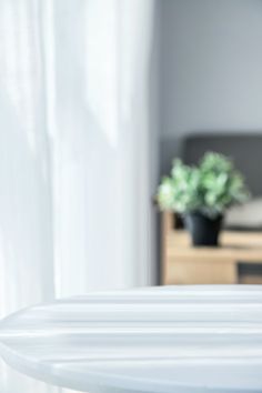 an alarm clock sitting on top of a white table next to a plant in a vase