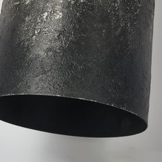 a black lamp shade hanging from a ceiling fixture with white and gray paint on it