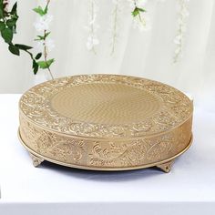 a round gold plate sitting on top of a table next to silverware and flowers