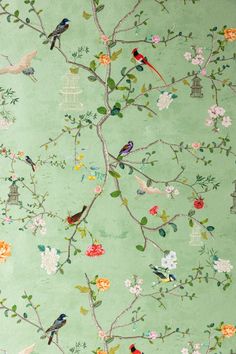 a green wallpaper with birds and flowers on the branches, in front of a birdcage