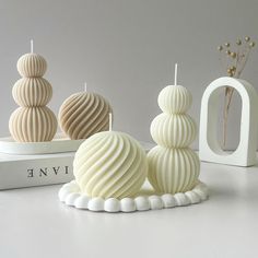 three white candles sitting next to each other on top of a book shelf with the word love spelled in front of them