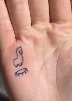 a person's hand with a small tattoo on the left side of their palm