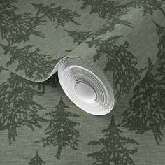 a green wallpaper with pine trees on it and white paper rolled up in the middle