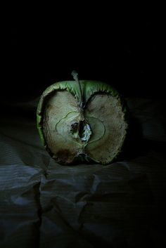 an apple that has been cut in half and is sitting on a bed with black sheets