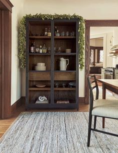 a wooden cabinet with glass doors in a living room next to a dining room table