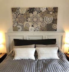 a bed with two pillows on top of it in front of a painting above the headboard