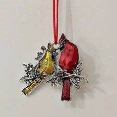 two birds on a branch ornament hanging from a red ribbon with silver accents