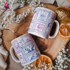 two coffee mugs sitting on top of a wooden table next to dried orange slices