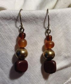 These earrings are beautiful!!  They are golden glass beads with antique silver and brown wood beads hanging from ear wires. Auburn Brown, Grey Beads, Dalmatian Jasper, Crochet Cowl, Etsy Earrings Dangle, Brown Wood, Auburn, Wood Beads, Ear Wires