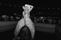 a black and white photo of a woman in a cowboy hat on top of a horse