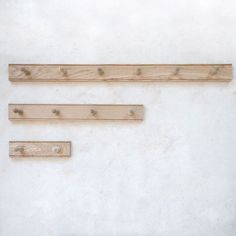 three pieces of wood sitting on top of a white wall next to eachother