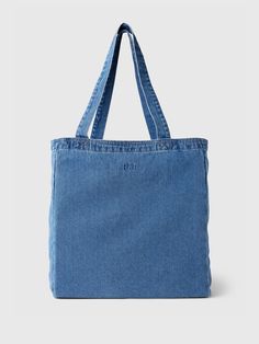 a denim tote bag is shown with the handles down and has an embroidered logo on it