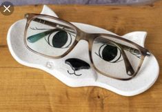 a pair of glasses sitting on top of a white cat shaped object with green eyes