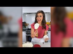 a woman standing in front of a counter holding an ice cream cone with flowers on it