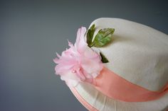 "DESCRIPTION * vintage hat from 1940s-1950s, deadstock-never been used * boater/ sailor style: high crown, with short brim * buckram hard frame is covered with off-white fabric * hatband is wrapped with pink grosgrain ribbon and forms a bow in the back * embellished with a pink flower and green leaves * comes with an elastic strap to secure the hat * no tag CONDITION * the hat has never been used, it is in good condition. There are two spots of wrinkle on the crown with small faded stains, pleas Vintage Pink Mini Hat With Short Brim, Vintage Pink Hat For Vacation, Vintage Pink Flat Brim Hat, Vintage Spring Straw Hat, Girls Easter Bonnet, Vintage Spring Hats, One Size, 1950s Hat, Bonnet Hat, Easter Bonnet