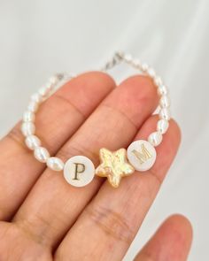 Add a touch of celestial elegance with this beautifully crafted bracelet, featuring a harmonious blend of freshwater rice pearls and a charming star-shaped pearl. Accented with two mother-of-pearl letter beads, this bracelet offers a personalized flair that makes it truly special. The centerpiece arrangement of letter, star, and letter beads can symbolize messages like "I ★ U" or "E ★ K," adding a unique and heartfelt touch. The bracelet is completed with a 925 sterling silver adjustable clasp, Star-shaped Jewelry With Pearl Charm As A Gift, Star-shaped Jewelry With Pearl Charm Gift, Elegant Pearl Bracelet With Letter Beads As Gift, Elegant Pearl Bracelet With Letter Beads For Gift, Pearl Bracelet With Letter Beads For Gift, White Charm Bracelet With Star Charm As Gift, Pearl Jewelry With Star Charm As A Gift, Pearl Jewelry With Star Charm For Gift, Star-shaped Pearl Jewelry For Gift