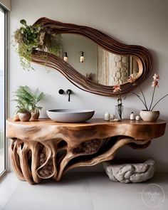 a wooden table with a bowl on it next to a mirror and potted plants