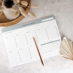 a table with an open planner and a pen on it next to a wicker basket