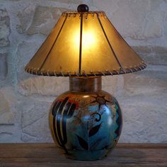 a lamp that is sitting on top of a wooden table next to a brick wall