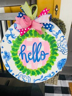 a hand painted plate with the word hello written in blue, pink and green on it