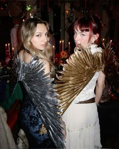 two beautiful women standing next to each other in front of a table with candles and decorations