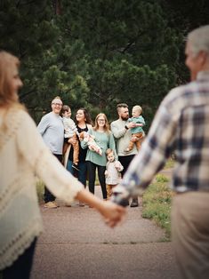 a group of people standing around each other in the park holding hands and smiling at one another