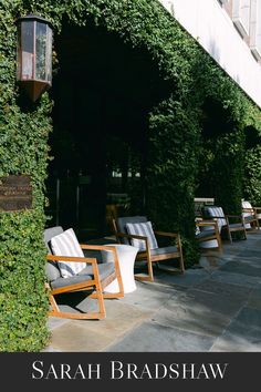 chairs are lined up on the side of a building with ivy growing over it's sides