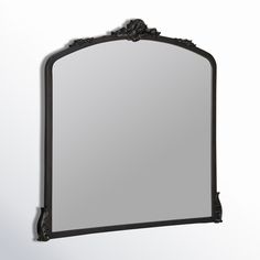 a mirror hanging on the wall with an ornate frame and black metal trimmings