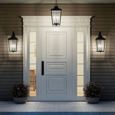 a white door with two planters on the front step and one light above it