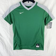 a green nike soccer jersey hanging on a hanger in front of a white sheet