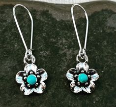 "Sweet and pretty little turquoise flower dangle earrings.  They are unique and versatile.  Dress them up or down.  The perfect everyday earrings. The flowers measure 1/2\" long 1/2\" wide.  They hang from kidney style ear wires that latch and lock.  Overall drop length is 1 1/2\". Made from plated silver. I have this same earring style also available with a red stone accent.  Here is a direct link https://www.etsy.com/listing/1387351493/ Thanks for stopping by!  Please take a moment and visit t Turquoise Teardrop Flower Earrings For Gift, Turquoise Flower Earrings As A Gift, Turquoise Flower Charm Earrings For Gift, Gift Turquoise Flower Charm Earrings, Gift Turquoise Flower Earrings, Turquoise Nickel Free Flower Earrings, Turquoise Dangle Earrings With Flower Charm, Nickel Free Turquoise Flower Earrings, Turquoise Flower-shaped Earrings With Flower Charm