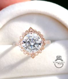 a close up view of a diamond ring on a white cloth with a hand holding it