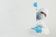 a man in white suit and blue gloves holding onto a blank sign with his hands