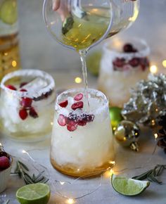 someone pouring wine into small glasses filled with ice and pomegranates, surrounded by christmas decorations