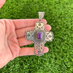 This gorgeous and rare cross pendant was created by Navajo artisan Albert Jake. Handmade from sterling silver, this pendant accents intricate deep stampwork detailed with symmetrical perfection, twist wire, and a natural purple sugiltie stone. Any lines on this stone are a part of its matrix and are not cracks or fractures. A unique, stand-out addition to any collection. Bale fits up to 10 millimeter Navajo Pearls (NOT included) Measures 2 1/2" long not including bale (3 1/4" long including bale Southwestern Style Purple Jewelry For Gift, Purple Southwestern Jewelry For Gifts, Purple Southwestern Jewelry For Gift, Purple Southwestern Style Jewelry For Gift, Handmade Southwestern Cross Pendant Jewelry, Handmade Southwestern Style Cross Pendant Jewelry, Bohemian Sterling Silver Cross Jewelry, Artisan Engraved Cross Pendant Jewelry, Artisan Sterling Silver Crucifix Jewelry