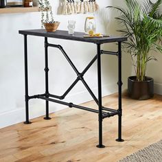 a black table sitting on top of a wooden floor next to a potted plant