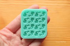 a hand holding a green mold that looks like an ice tray with dogs on it