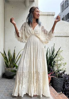 a woman in a white dress is standing on a porch with her arms out and one hand up