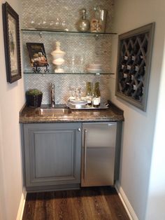 a small kitchen with stainless steel appliances and glass shelves on the wall above the sink