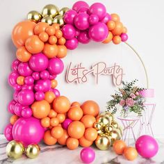 the balloon arch is decorated with pink, orange and gold balloons that spell out let's party