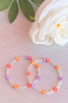 two bracelets sitting next to a white flower