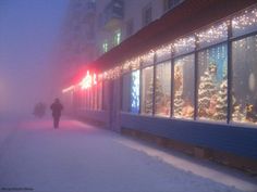 a person walking down the street in front of a store with christmas lights on it