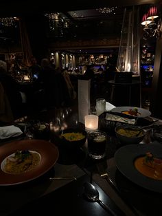 a table filled with plates and bowls of food next to candles on top of it