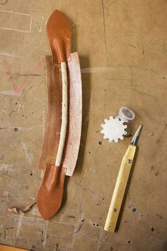 a pair of scissors and some leathers on a table next to a piece of wood