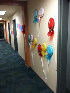 some lollipops are hanging on the wall in an office hallway with blue carpeting