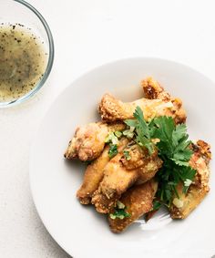 a white plate topped with fried food next to a glass of liquid