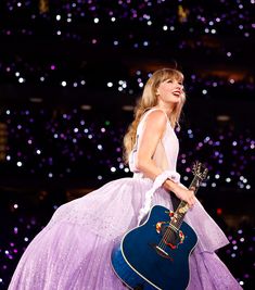 a woman in a purple dress holding a guitar