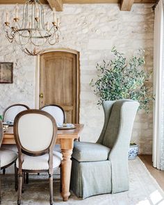 a dining room table with chairs and a chandelier hanging from the ceiling above it